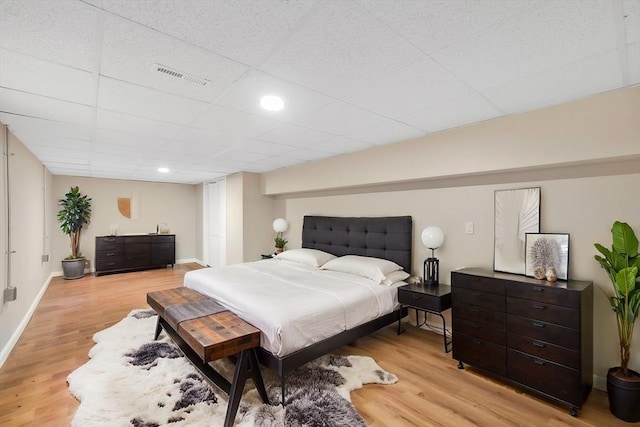 bedroom with visible vents, a paneled ceiling, light wood-style floors, and baseboards