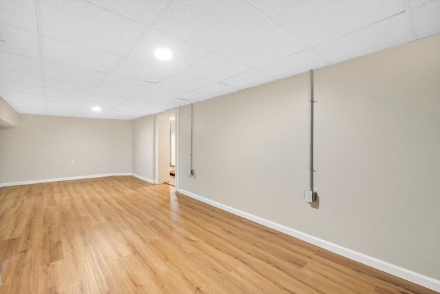 finished below grade area featuring a drop ceiling, light wood-type flooring, baseboards, and recessed lighting