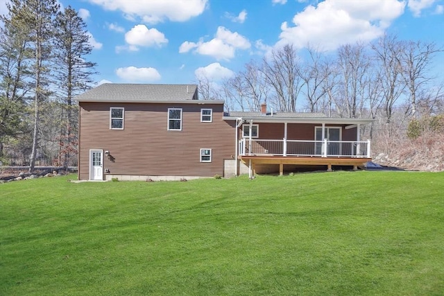 rear view of house with a wooden deck, a lawn, and a chimney