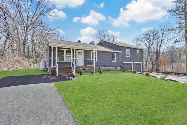 tri-level home with driveway, an attached garage, a porch, and a front lawn