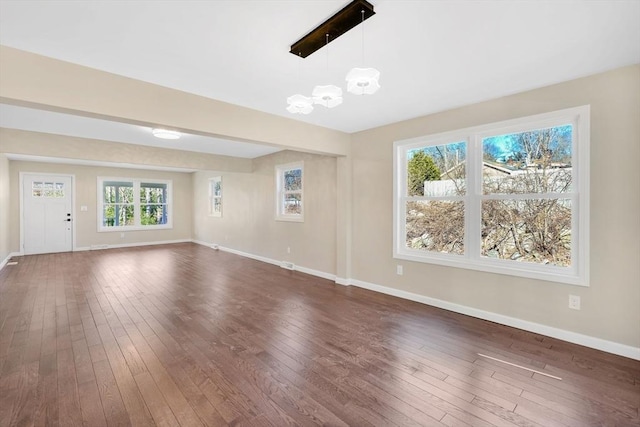 unfurnished living room with dark wood-style floors, baseboards, and a chandelier