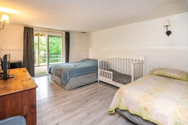 bedroom with light hardwood / wood-style floors, access to outside, and a textured ceiling