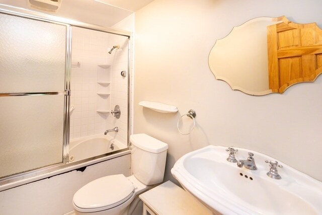 full bathroom featuring shower / bath combination with glass door, toilet, and sink