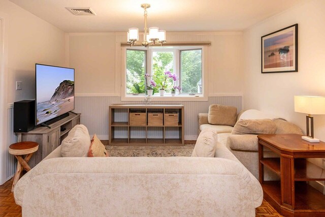 living room featuring a notable chandelier and dark parquet flooring