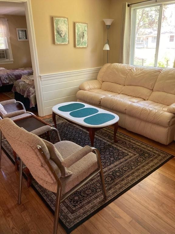 living room with a healthy amount of sunlight, cooling unit, and wood-type flooring