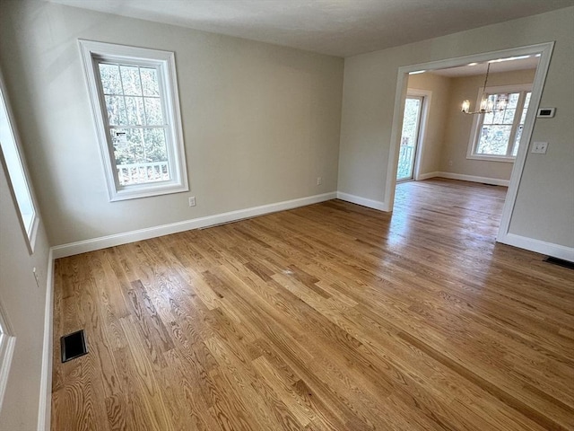 unfurnished room with hardwood / wood-style floors and a notable chandelier