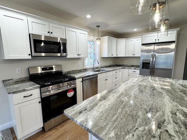 kitchen with white cabinetry, hanging light fixtures, stainless steel appliances, and sink