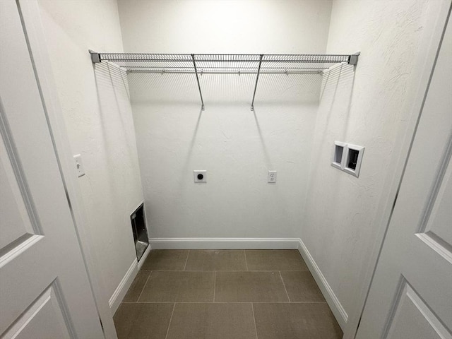 clothes washing area featuring hookup for an electric dryer, dark tile patterned flooring, and hookup for a washing machine