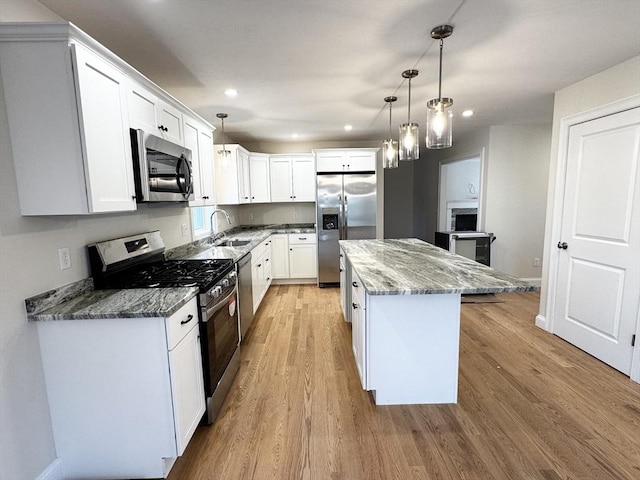 kitchen with white cabinetry, appliances with stainless steel finishes, a center island, and dark stone counters