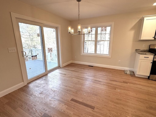 unfurnished dining area featuring a chandelier and light hardwood / wood-style flooring