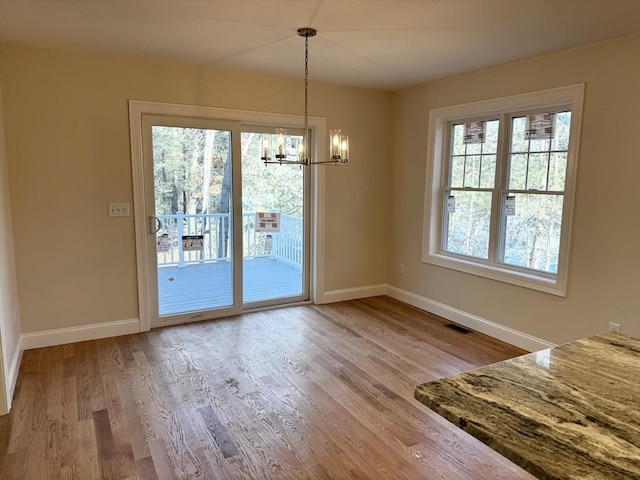 unfurnished dining area featuring wood-type flooring and a chandelier