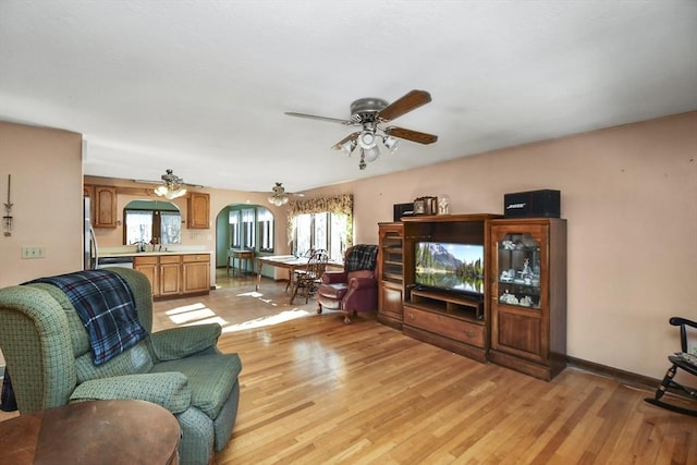 living room with sink, light hardwood / wood-style floors, and ceiling fan