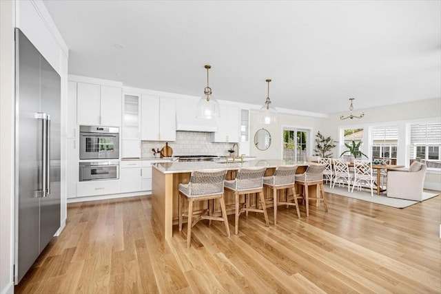 34 Otis Hill Rd, Hingham, MA 02043 - kitchen with appliances with stainless steel finishes, light wood-style flooring, a kitchen breakfast bar, a chandelier, and pendant lighting