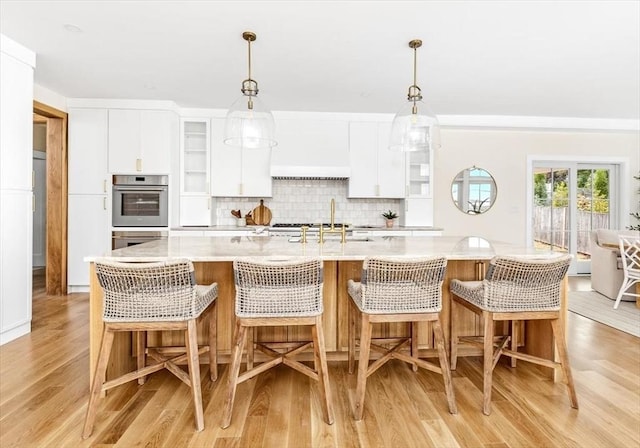 34 Otis Hill Rd, Hingham, MA 02043 - kitchen with light wood-style flooring, a sink, backsplash, white cabinets, and hanging light fixtures