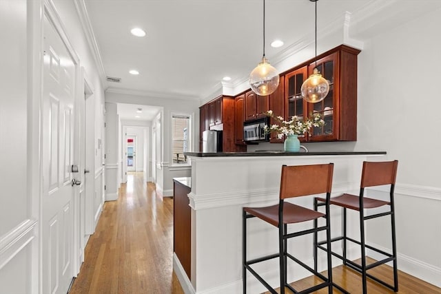 53 Woodward St Unit 2, Boston, MA 02127 - kitchen with appliances with stainless steel finishes, a breakfast bar area, light wood-style flooring, recessed lighting, and dark countertops