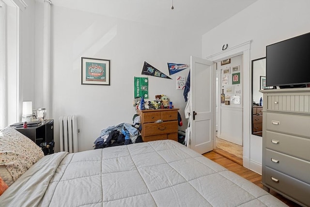 bedroom with radiator and wood finished floors