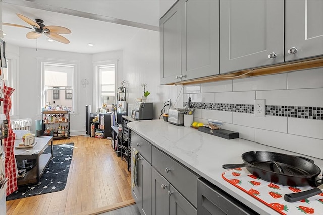 kitchen with light wood-type flooring, ceiling fan, tasteful backsplash, and gray cabinets