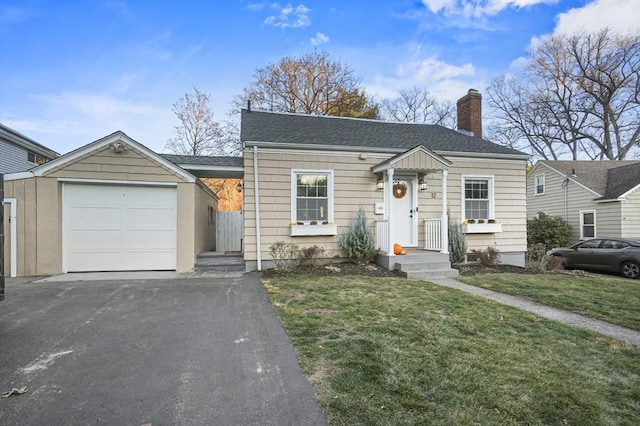 bungalow-style home featuring driveway, a garage, a shingled roof, a chimney, and a front yard