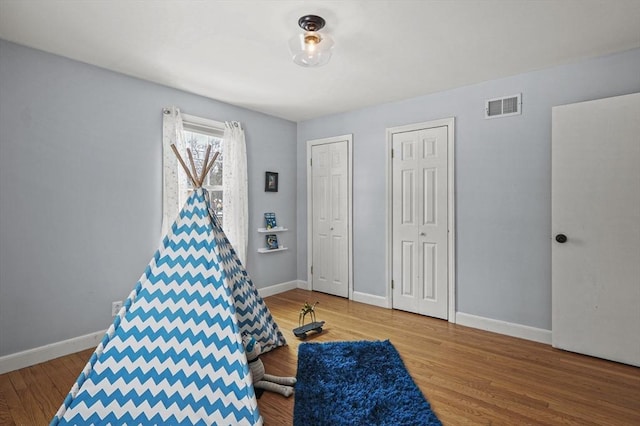 game room featuring wood finished floors, visible vents, and baseboards