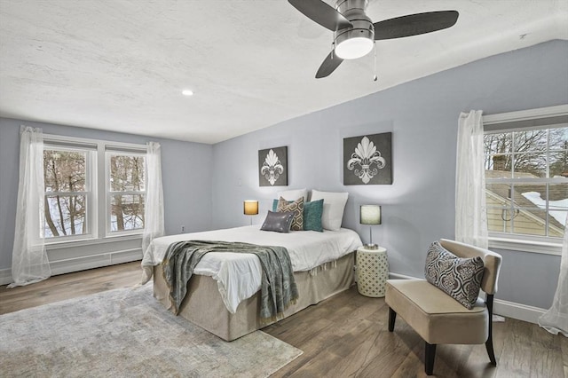 bedroom featuring multiple windows, baseboards, vaulted ceiling, and wood finished floors