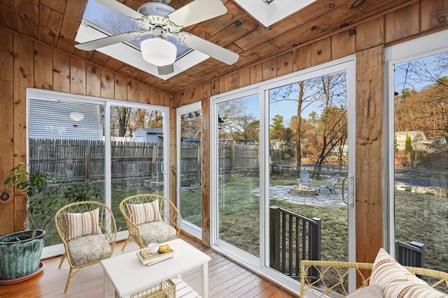 sunroom featuring wooden ceiling, lofted ceiling with skylight, and a ceiling fan