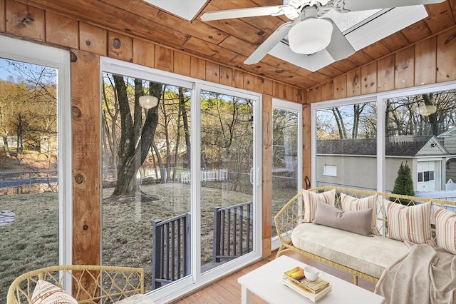 sunroom / solarium featuring wood ceiling, lofted ceiling with skylight, plenty of natural light, and ceiling fan