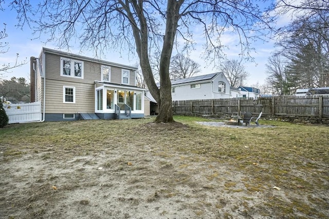 back of house with a sunroom, an outdoor fire pit, and a fenced backyard