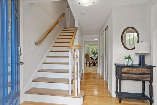 foyer entrance with light wood finished floors, stairway, and baseboards