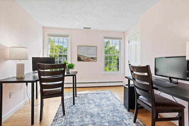 office featuring a baseboard heating unit, light wood-type flooring, and baseboards