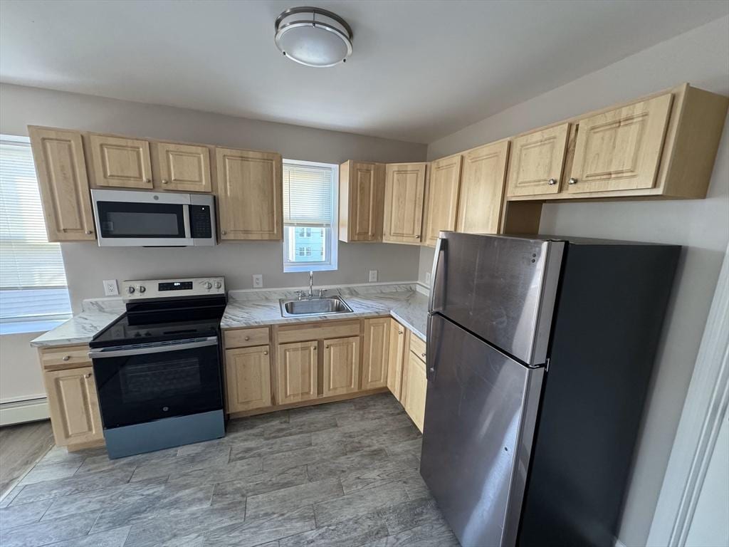 kitchen featuring light brown cabinets, sink, appliances with stainless steel finishes, and a baseboard radiator