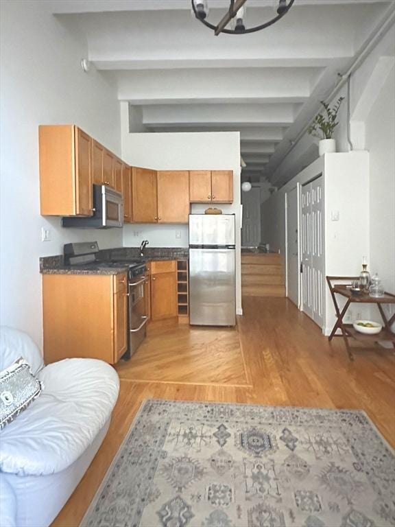 kitchen with beamed ceiling, light wood-type flooring, and appliances with stainless steel finishes