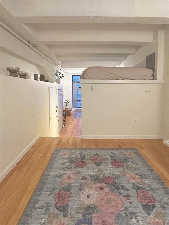 corridor with hardwood / wood-style floors and beamed ceiling