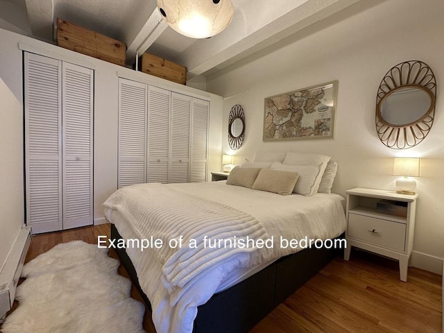 bedroom with beam ceiling, two closets, and hardwood / wood-style flooring