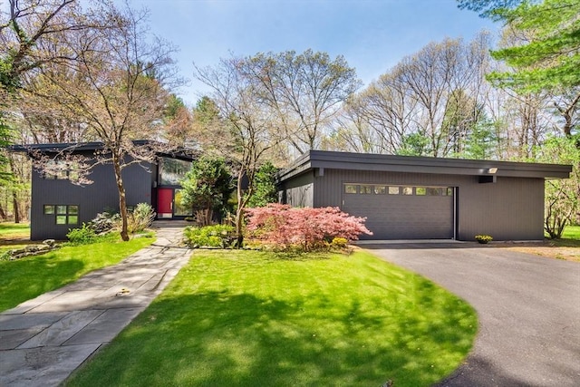 mid-century home with an attached garage, driveway, and a front yard