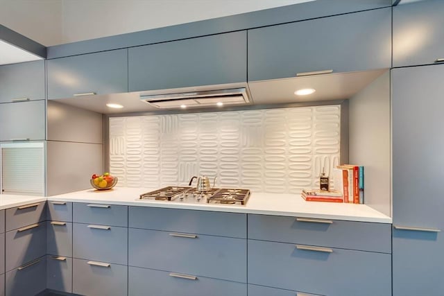kitchen featuring tasteful backsplash, light countertops, gray cabinetry, stainless steel gas stovetop, and extractor fan