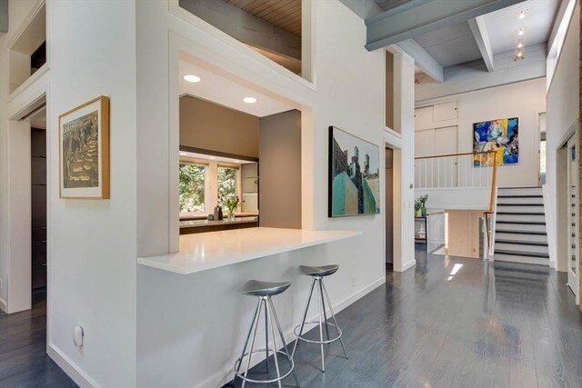 interior space with baseboards, dark wood finished floors, beam ceiling, and stairway