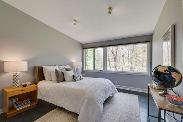 bedroom with baseboards, a baseboard radiator, lofted ceiling, and wood finished floors