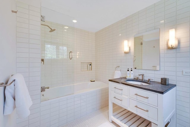bathroom with vanity, tile patterned floors, tiled shower / bath, and tile walls