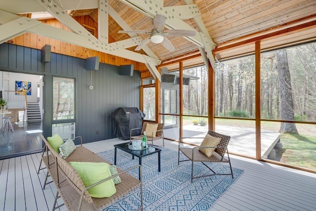 sunroom / solarium with a ceiling fan and beam ceiling