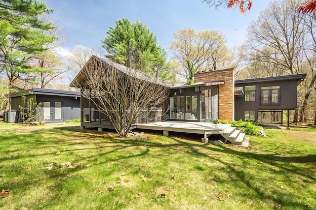 back of house featuring a lawn, a deck, central AC unit, and a chimney