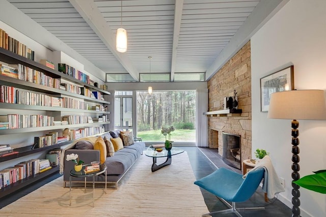 sitting room featuring a stone fireplace, beam ceiling, and wood finished floors