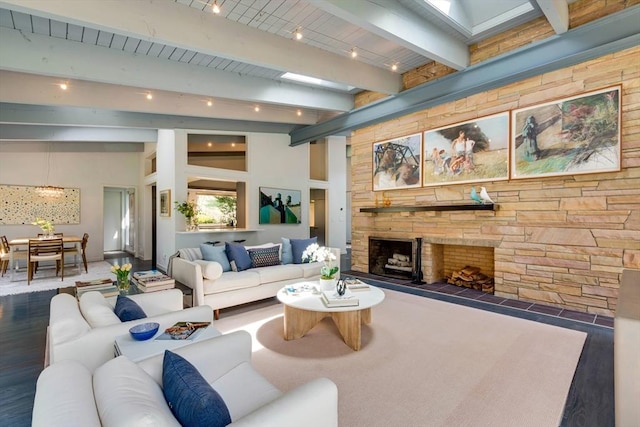 living room featuring beamed ceiling, a stone fireplace, and wood finished floors