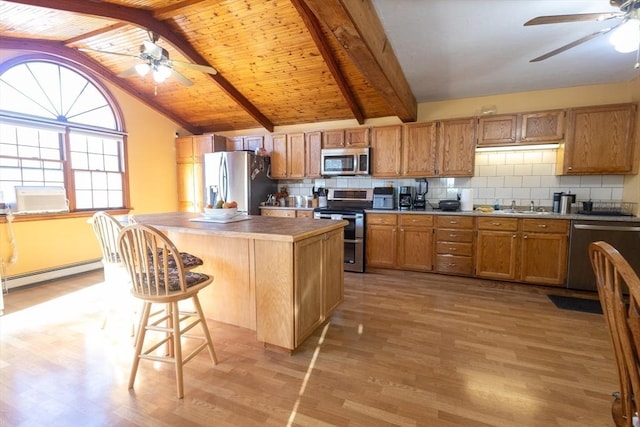 kitchen with a breakfast bar, a center island, baseboard heating, stainless steel appliances, and light hardwood / wood-style flooring