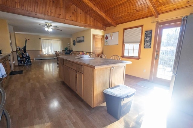 kitchen with vaulted ceiling with beams, a baseboard radiator, a kitchen island, and light brown cabinets