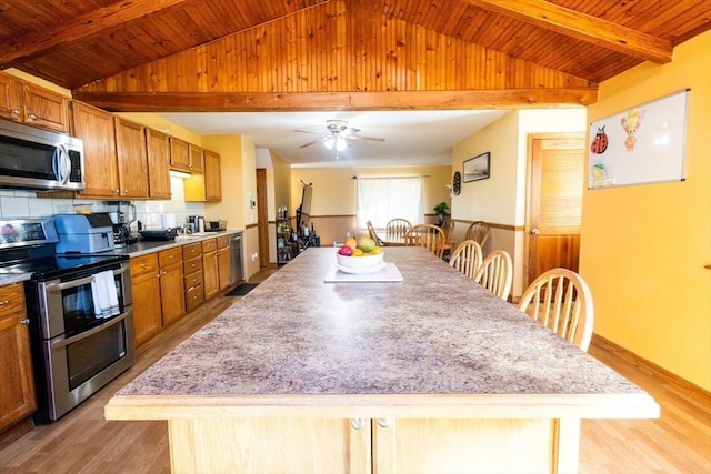 kitchen featuring appliances with stainless steel finishes, a center island, vaulted ceiling with beams, and wooden ceiling