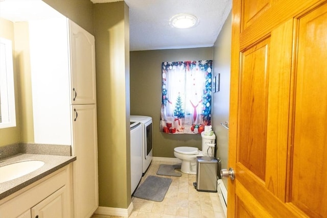 bathroom featuring vanity, a baseboard heating unit, washing machine and clothes dryer, and toilet