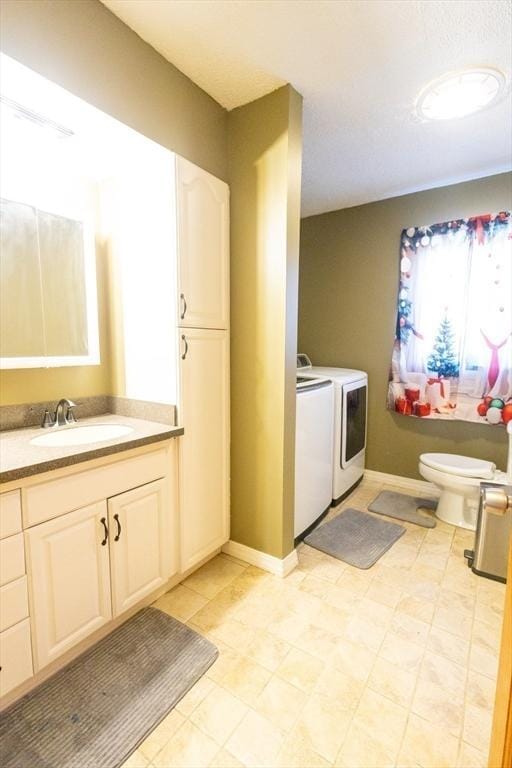 bathroom with vanity, washer and clothes dryer, and toilet