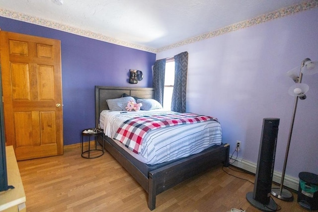 bedroom with wood-type flooring and baseboard heating