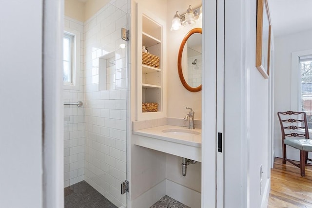 bathroom with a stall shower, a sink, and wood finished floors