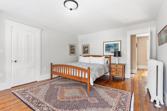 bedroom featuring radiator, baseboards, and wood finished floors